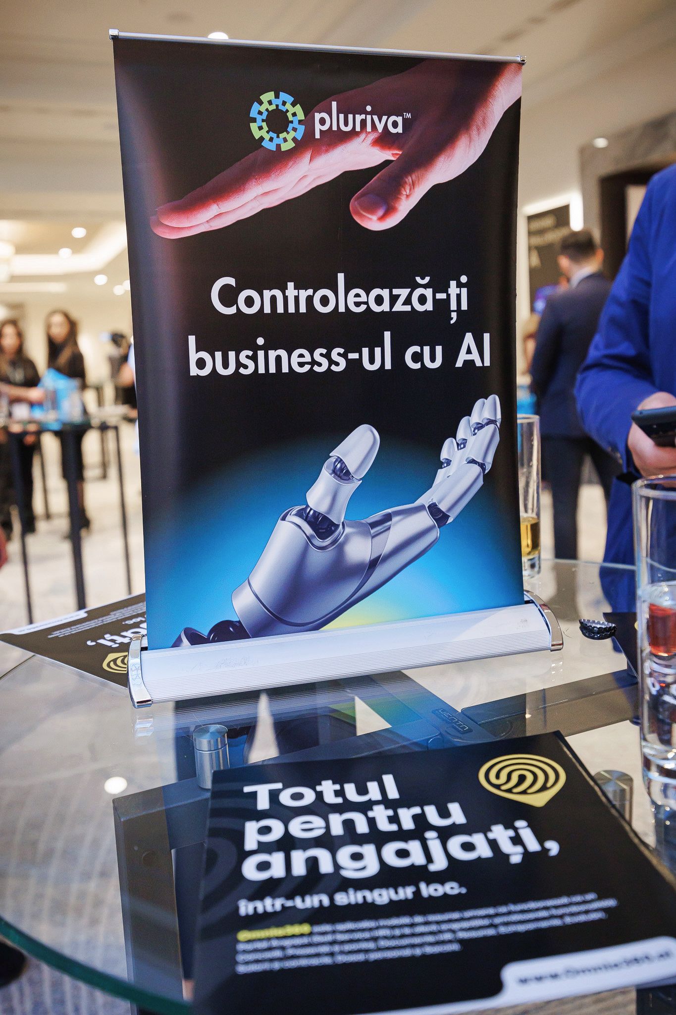 Roll-up Pluriva pe o masă, cu textul „Controlează-ți business-ul cu AI”