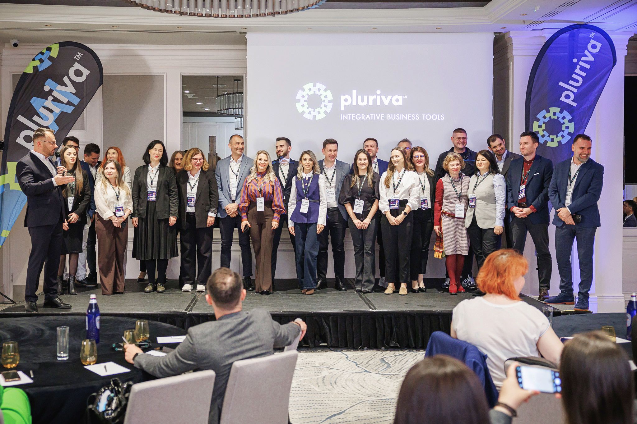 Echipa Pluriva pe scenă, în fața siglei pluriva integrative business tools